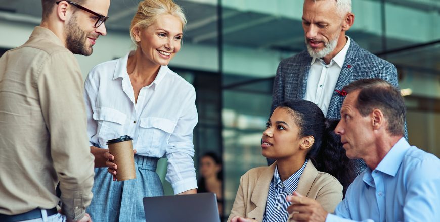 Having a meeting. Group of multiracial business people in classic wear working together on a new project while sitting together in the office, using laptop